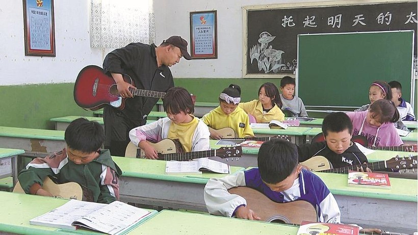 Song Hao dạy học sinh chơi guitar trong một trường tiểu học ở Gaozhuang thuộc Zhongwei, khu tự trị Ningxia Hui. Ảnh: China Daily