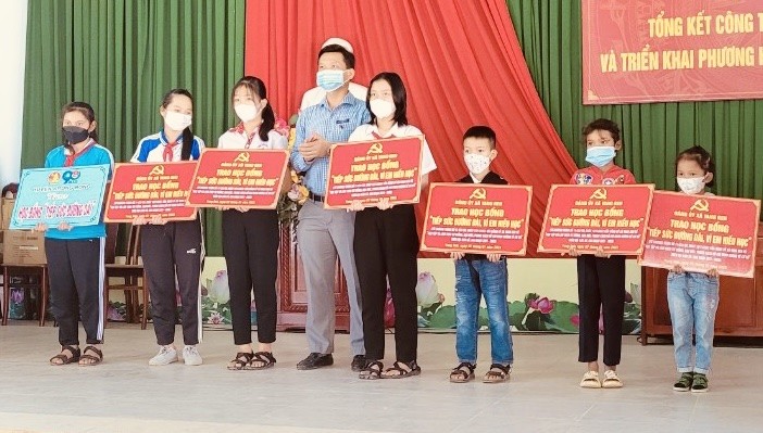 Ông Hoàng Thế Nhân - Bí thư Đảng uỷ xã trao hỗ trợ cho học sinh.
