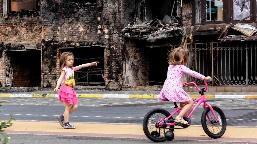 Trẻ em Ukraine vui chơi bên ngoài một tòa nhà bị tàn phá bởi chiến tranh.