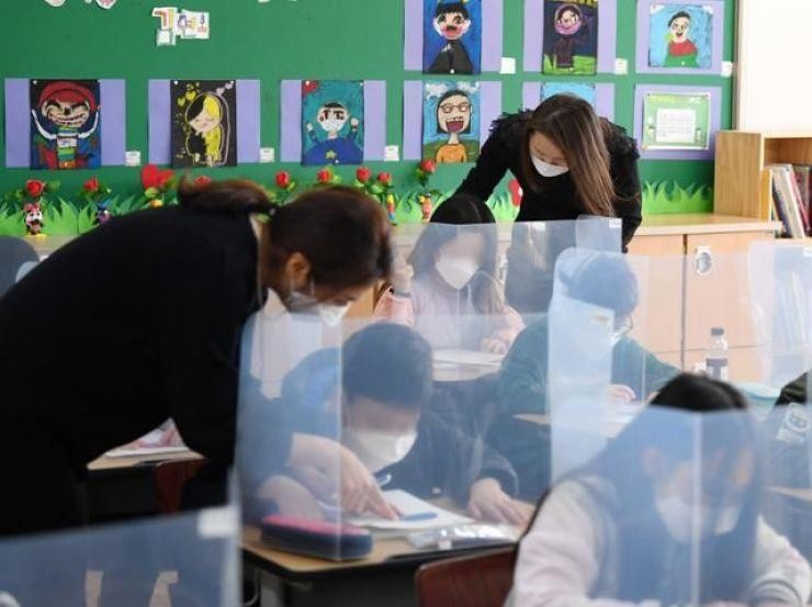 Giáo viên một trường tiểu học tại Seoul giúp học sinh giải toán.