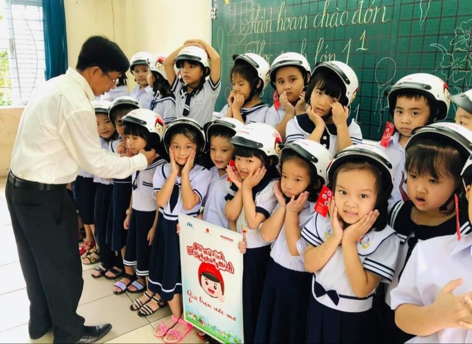 Hiệu trưởng Trường Tiểu học Võ Thị Sáu (quận Hải Châu) hướng dẫn HS đội mũ bảo hiểm khi tham gia giao thông.