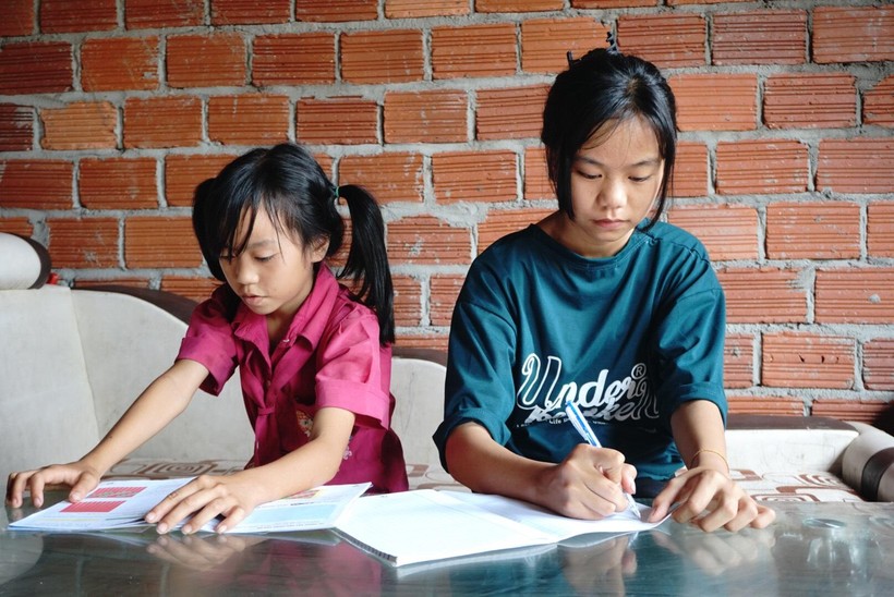 Em Bùi Thị Châu (bên phải) cùng người em gái học bài. 
