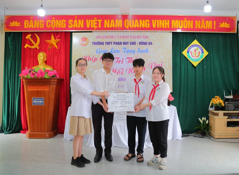 Các em học sinh Trường THPT Phan Huy Chú - Đống Đa (trái) trao tặng sách cho đại diện học sinh Trường THCS Đông La (Hoài Đức, Hà Nội).
